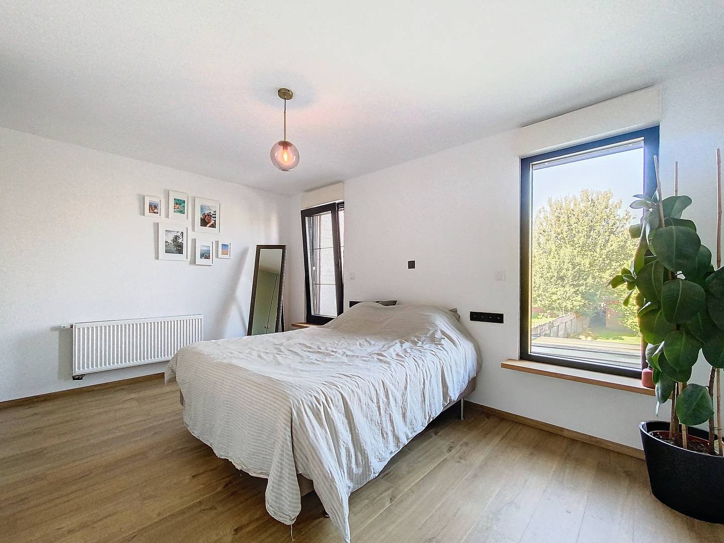 Slaapkamer 1 met houten vloer en groot raam
