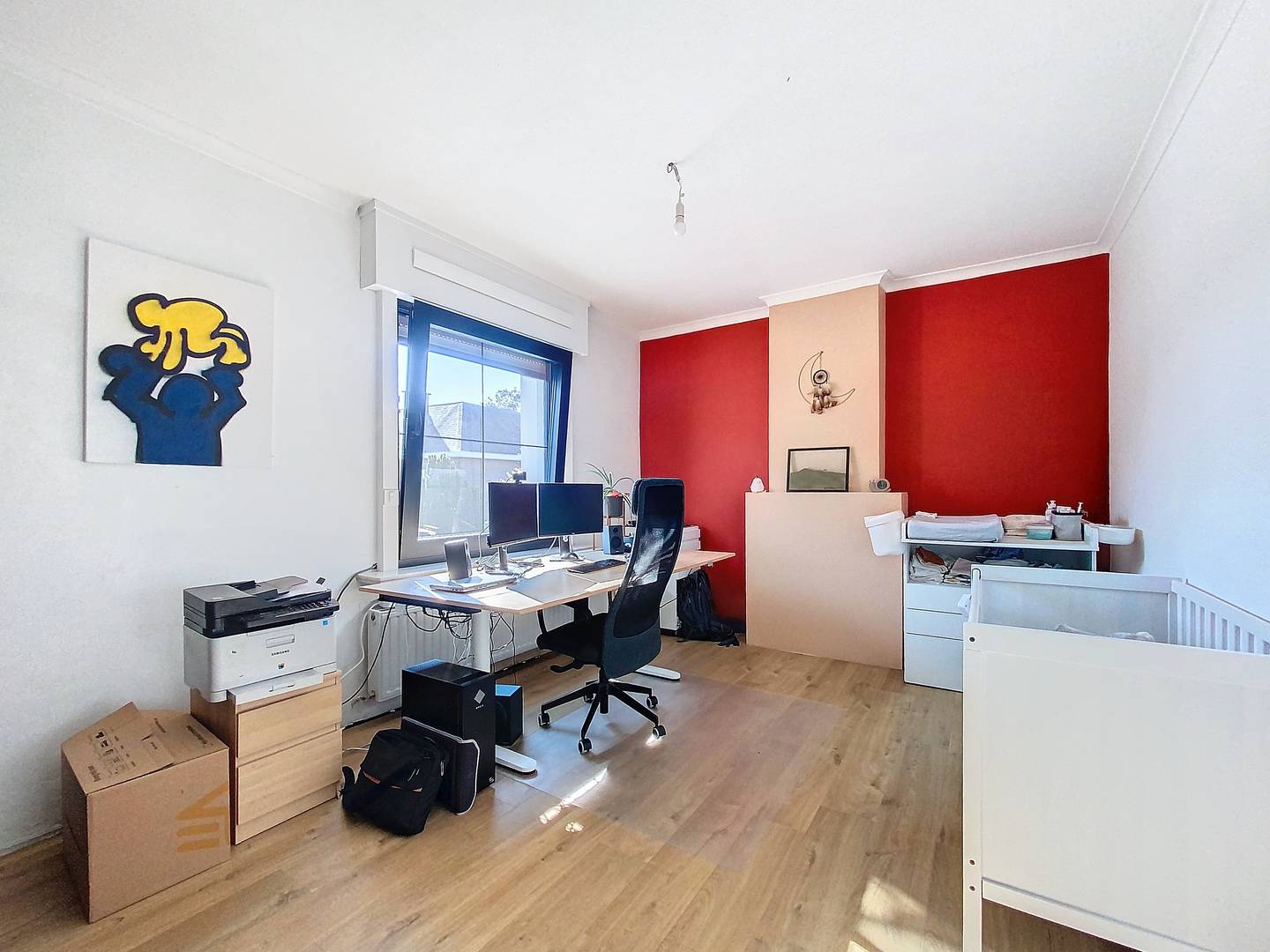 Slaapkamer 2 met houten vloer, raam op de straat en rode accentmuur